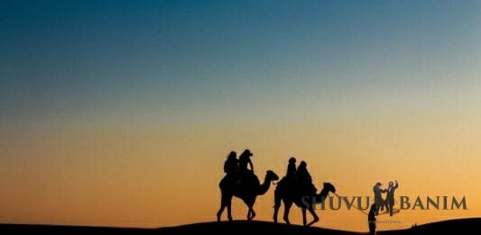 Picture of two people in silhouette riding camels in the desert